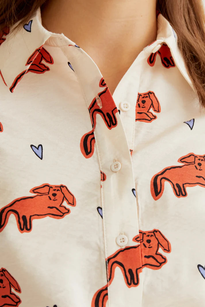 Women's cream printed button-up shirt featuring artistic coral colored dog illustrations, long sleeves and modern boutique style.