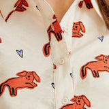 Women's cream printed button-up shirt featuring artistic coral colored dog illustrations, long sleeves and modern boutique style.