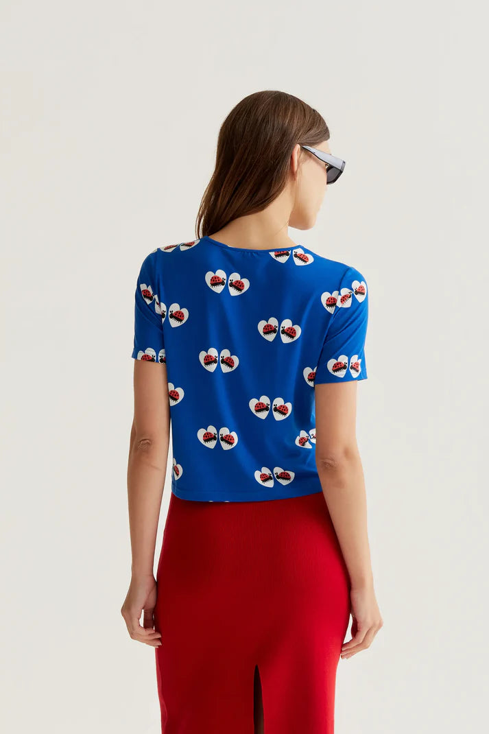 Bright cobalt blue short sleeve knit top featuring whimsical ladybug heart print and lightweight fabric for casual everyday wear.