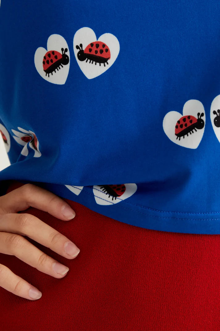 Lightweight royal blue knit top with ladybug heart pattern, short sleeves and contemporary cropped fit for vacations and casual styling.
