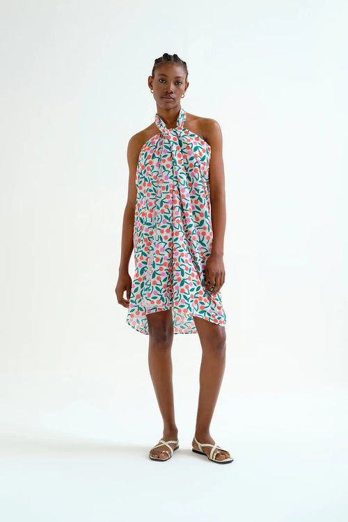 Young woman wearing a casual summer sarong with green, orange and pink cherry pattern.  Fun, sporty, beachy.