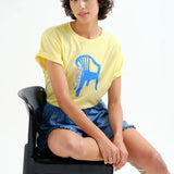 Trendy pastel yellow graphic top with rolled sleeves and bold contemporary illustration for effortless street style.