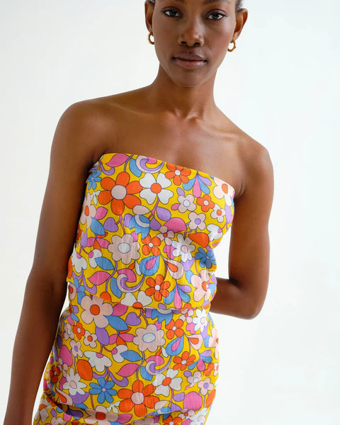 Woman wearing a hippy, boho chic, colorful floral sarong dress on a white background.  Sporty beachy.