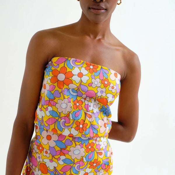 Woman wearing a hippy, boho chic, colorful floral sarong dress on a white background.  Sporty beachy.