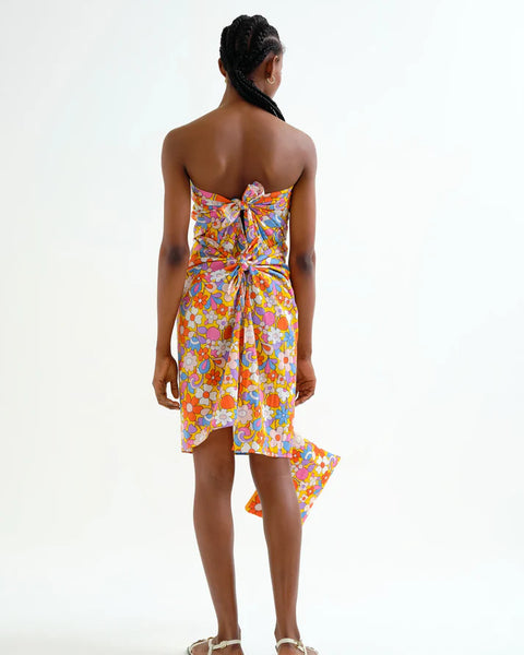 Back view, showing the back ties on a woman wearing a colorful floral sarong dress on a white background.  Sporty beachy.