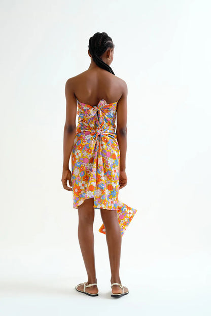 Back view, showing the back ties on a woman wearing a colorful floral sarong dress on a white background.  Sporty beachy.