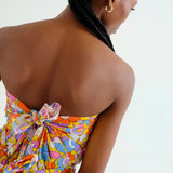 Back view, close-up of a woman wearing a hippy, boho chic, colorful floral sarong on a white background.  Sporty beachy.