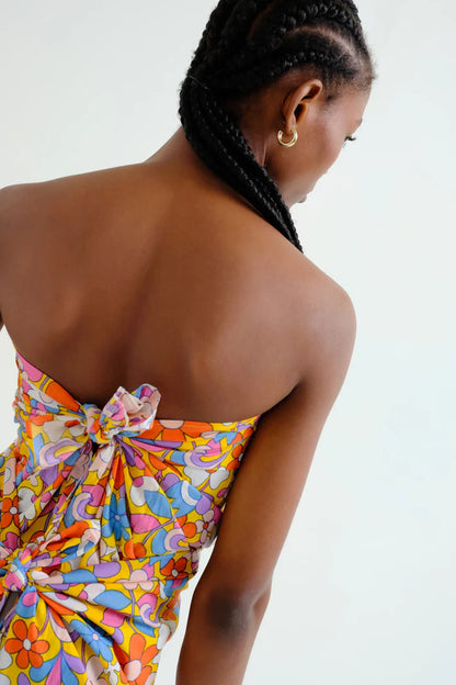 Back view, close-up of a woman wearing a hippy, boho chic, colorful floral sarong on a white background.  Sporty beachy.