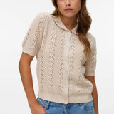 Soft neutral pointelle knit sweater cardigan with short sleeves, button-front closure and vintage-inspired silhouette for spring and summer layering.