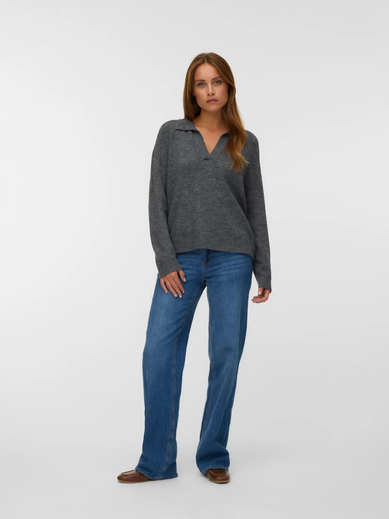 Charcoal grey knit pullover for women with a polo collar, V-neckline and relaxed silhouette styled with blue jeans.