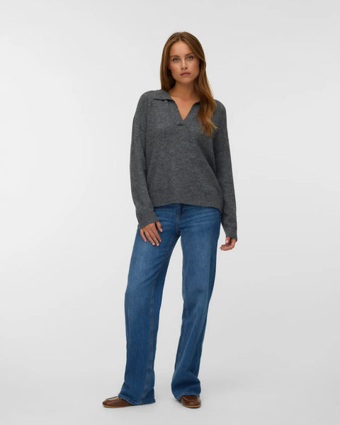 Charcoal grey knit pullover for women with a polo collar, V-neckline and relaxed silhouette styled with blue jeans.
