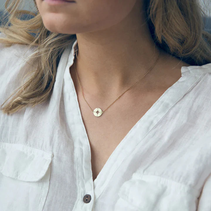 Women’s delicate gold compass rose necklace with fine chain and minimalist medallion pendant.
Ele