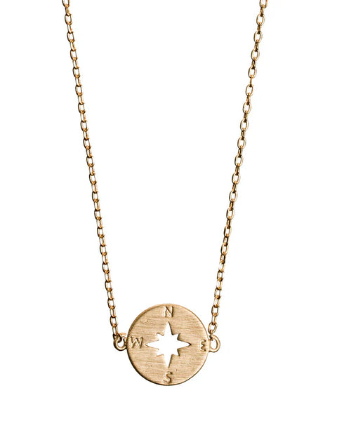 Gold layering necklace featuring a compass disc pendant and minimalist jewelry design.