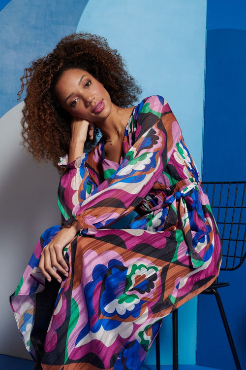 Elegant multicolor printed dress with cinched waist tie and sheer long sleeves for modern feminine occasion styling.