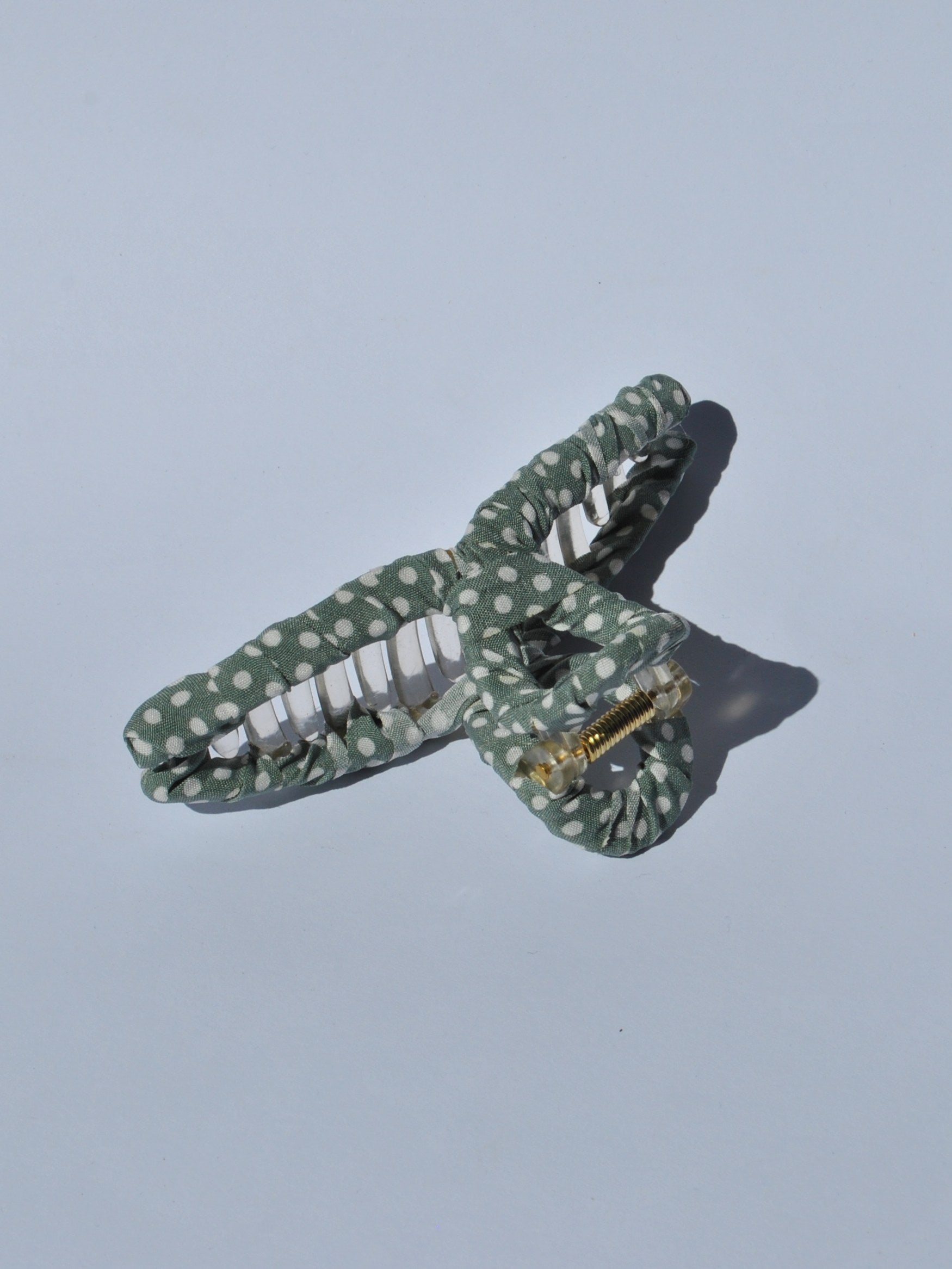 Fashion-forward women’s claw clip featuring soft green fabric and white dot print for easy messy bun hairstyles.