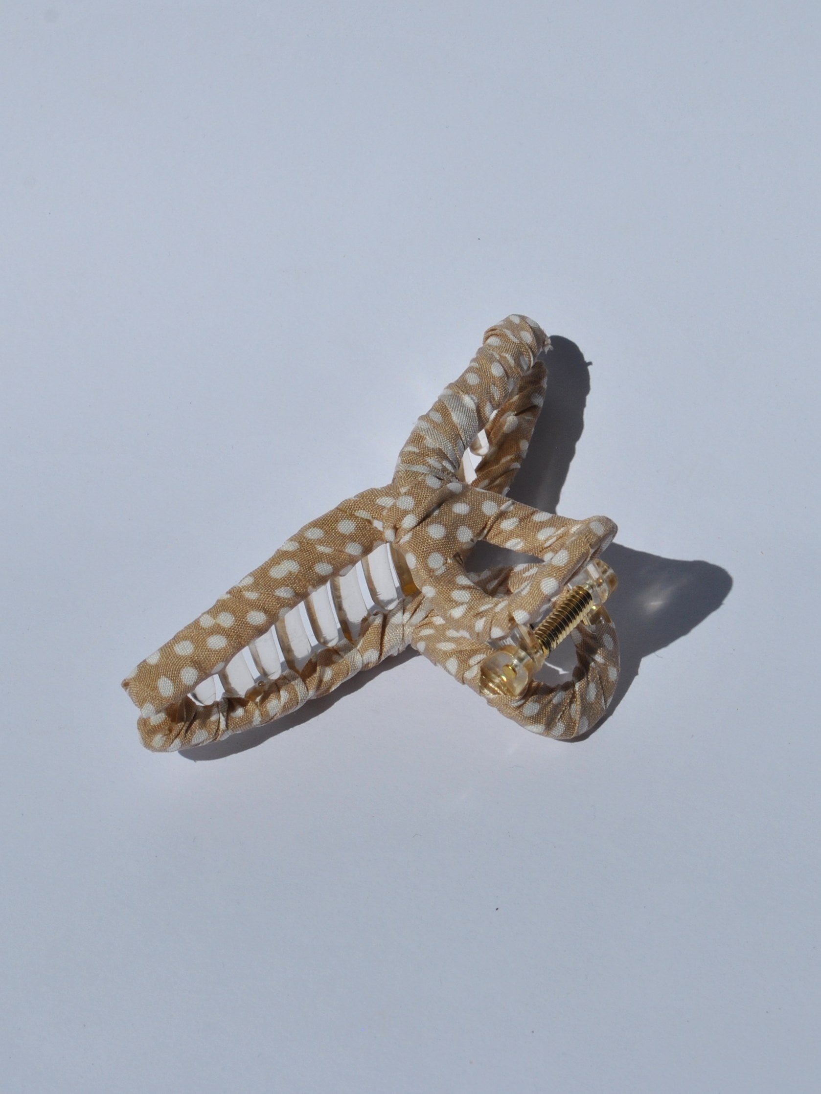 Women’s trendy claw hair clip in gold and white polka dot print with oversized shape for quick effortless hairstyles.