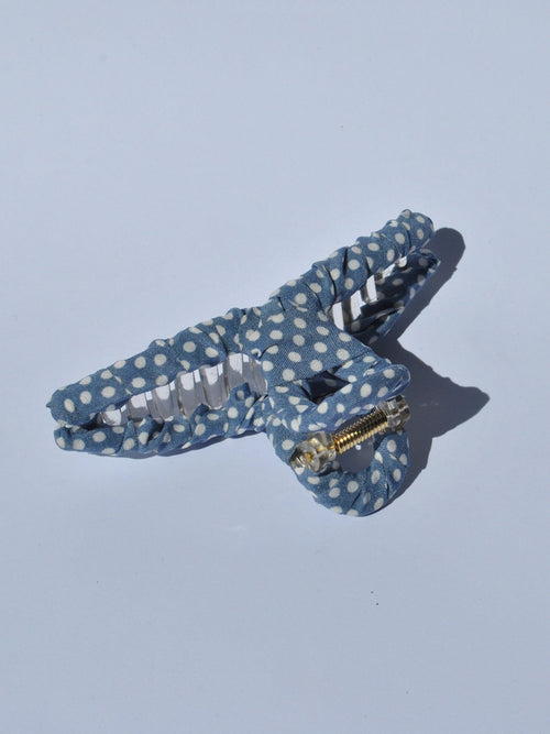 Vintage-inspired blue polka dot hair claw with strong transparent clip and trendy retro fashion aesthetic.