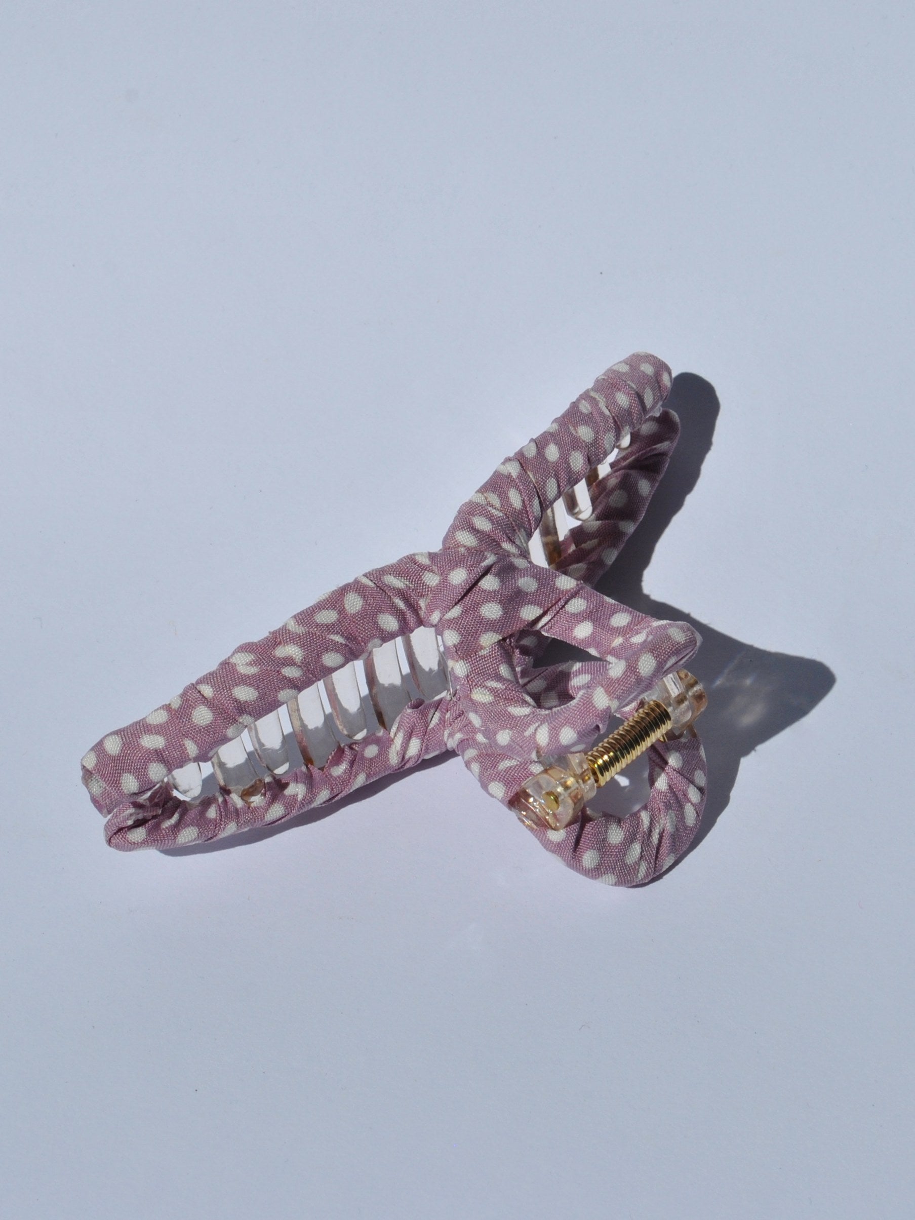 Soft fabric claw clip with playful white polka dots and clear acrylic grip for modern feminine hair styling.