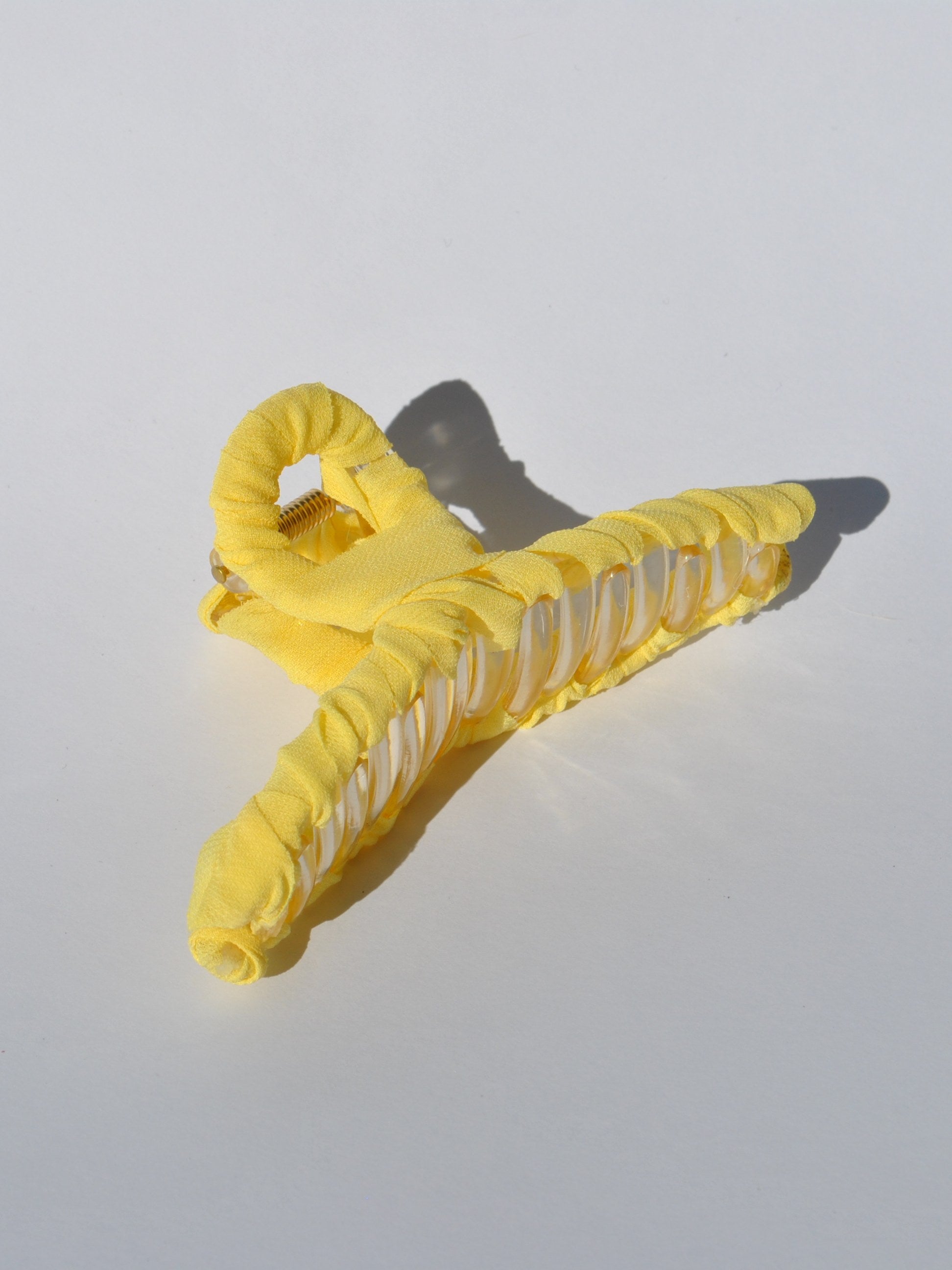 Bright yellow fabric-covered claw clip with translucent details and modern minimalist aesthetic.