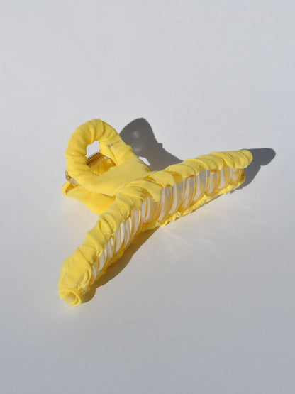 Bright yellow fabric-covered claw clip with translucent details and modern minimalist aesthetic.