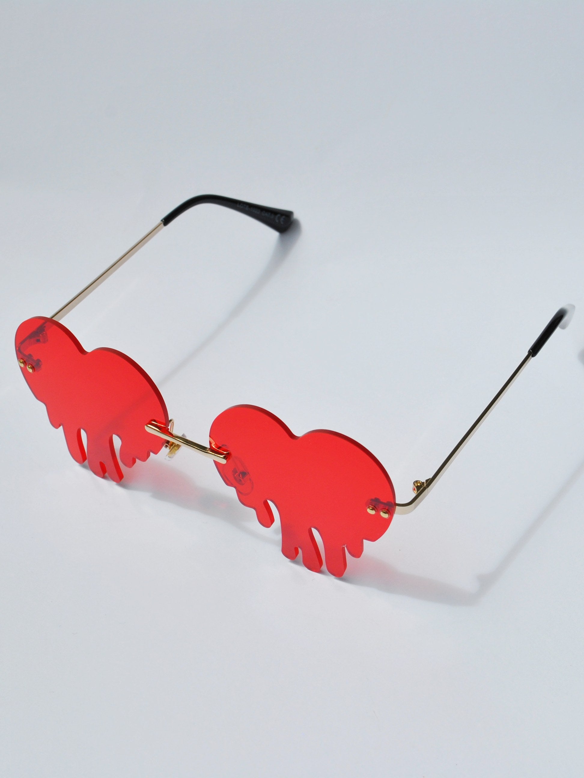 Unique red dripping heart sunglasses with rimless tinted lenses and gold metal frame.