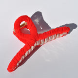 Fashion hair accessory featuring bright red fabric and oversized claw construction.