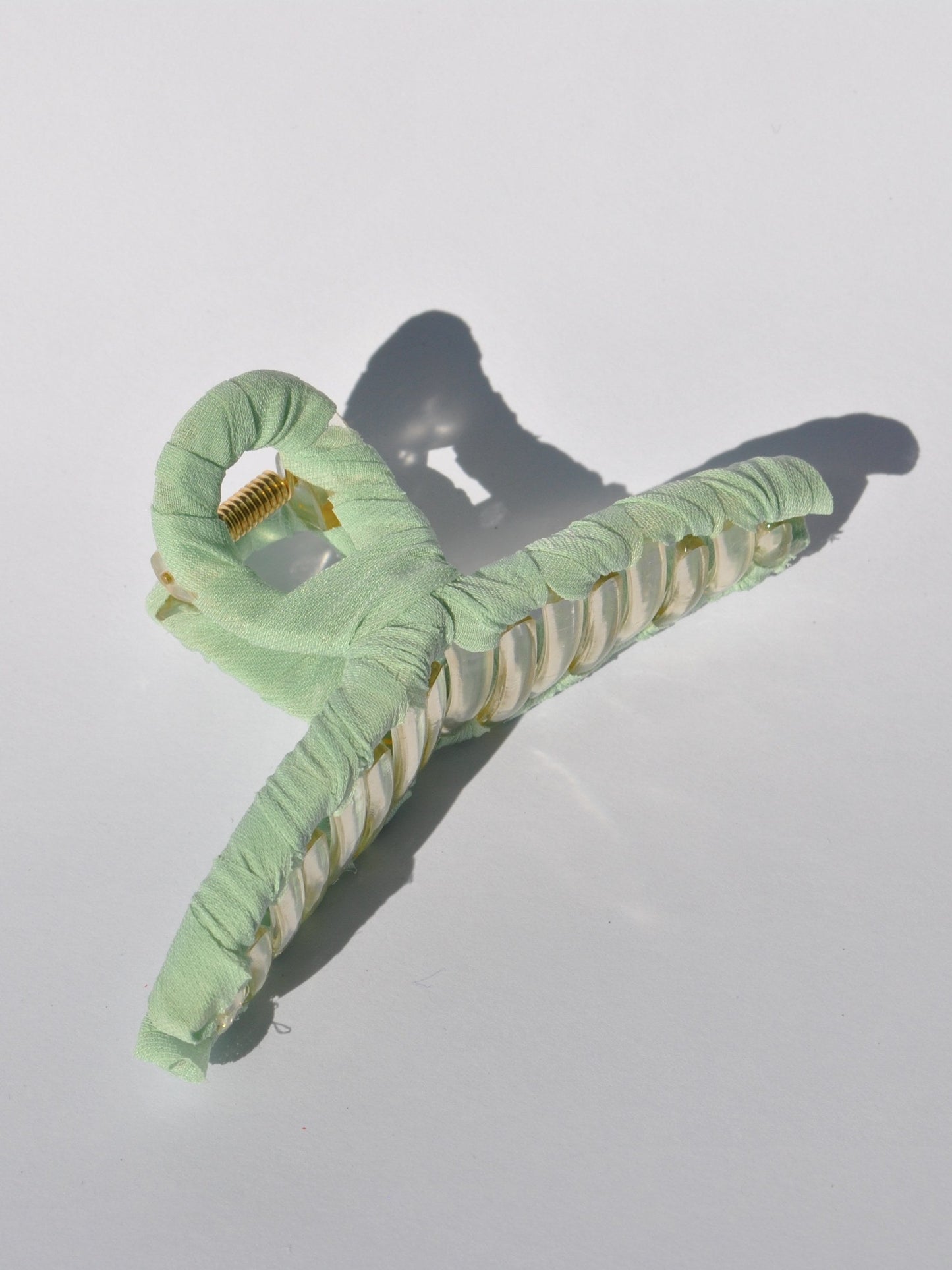 Fashionable mint claw clip with translucent acrylic frame and soft fabric covering.