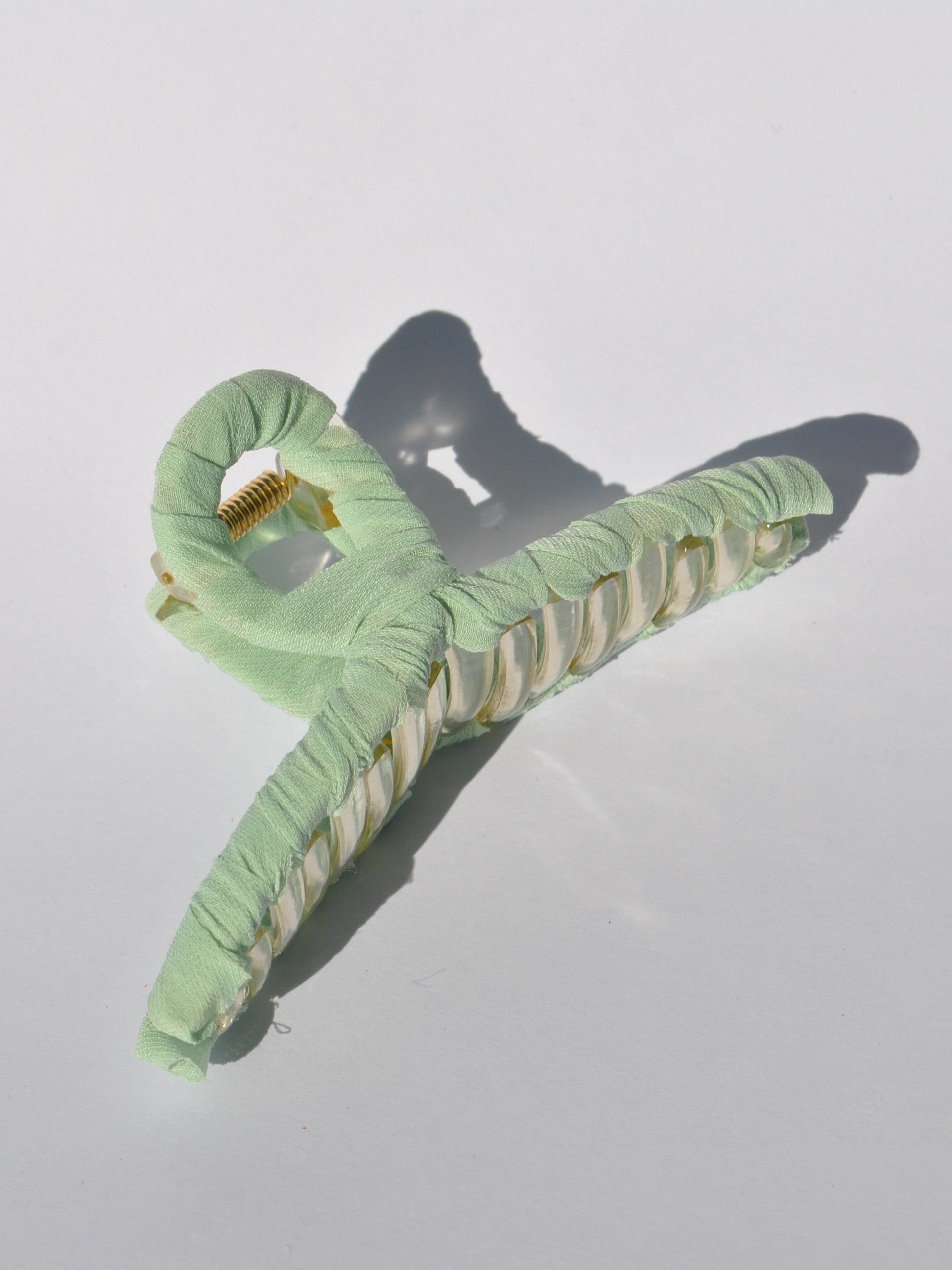 Fashionable mint claw clip with translucent acrylic frame and soft fabric covering.