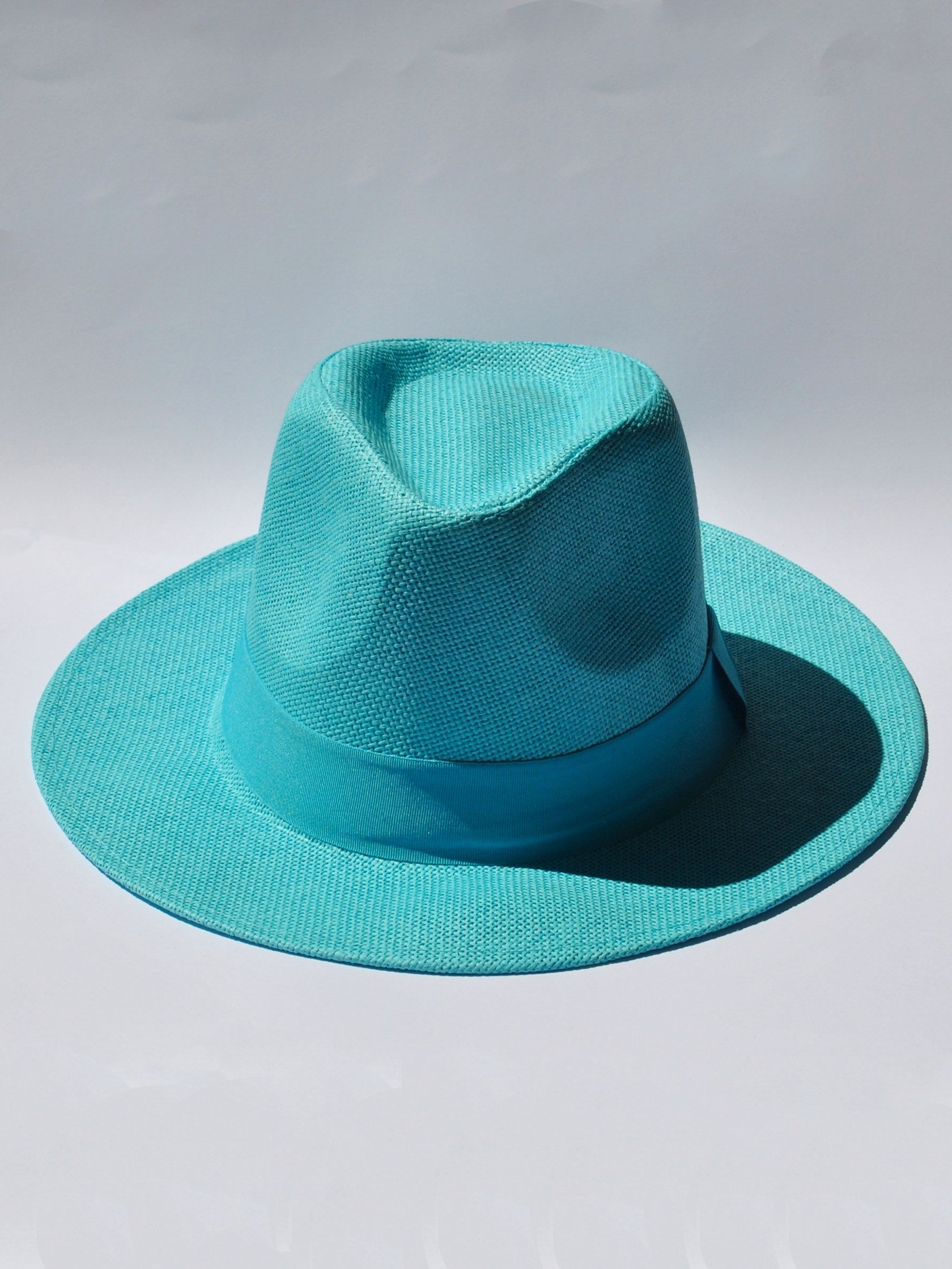 Women's turquoise wide brim fedora hat with woven texture and matching ribbon band for summer vacations.