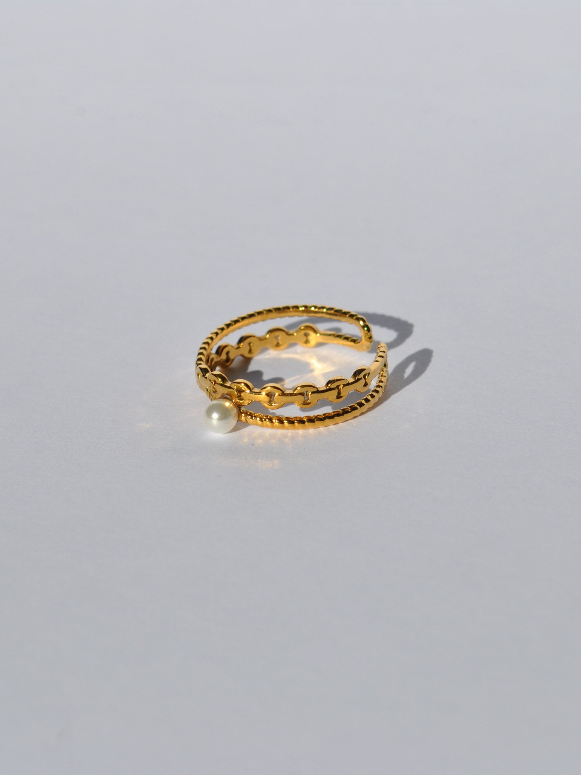 Women’s gold wraparound ring with textured detailing and elegant pearl centerpiece for stylish day-to-night outfits.
