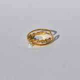 Women’s gold wraparound ring with textured detailing and elegant pearl centerpiece for stylish day-to-night outfits.