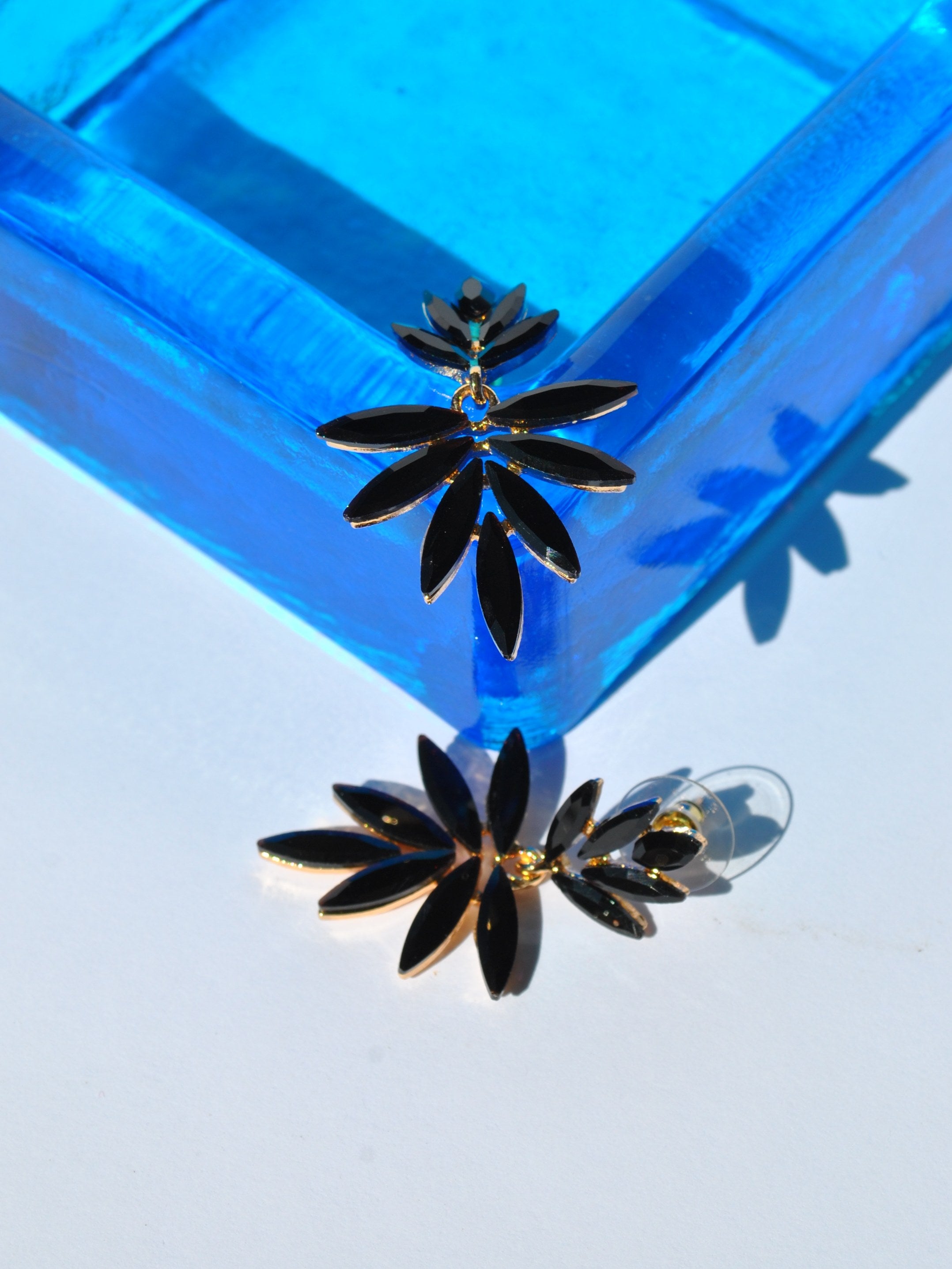 Luxury-inspired black petal earrings with sparkling faceted stones and elegant gold hardware for evening wear fashion.
