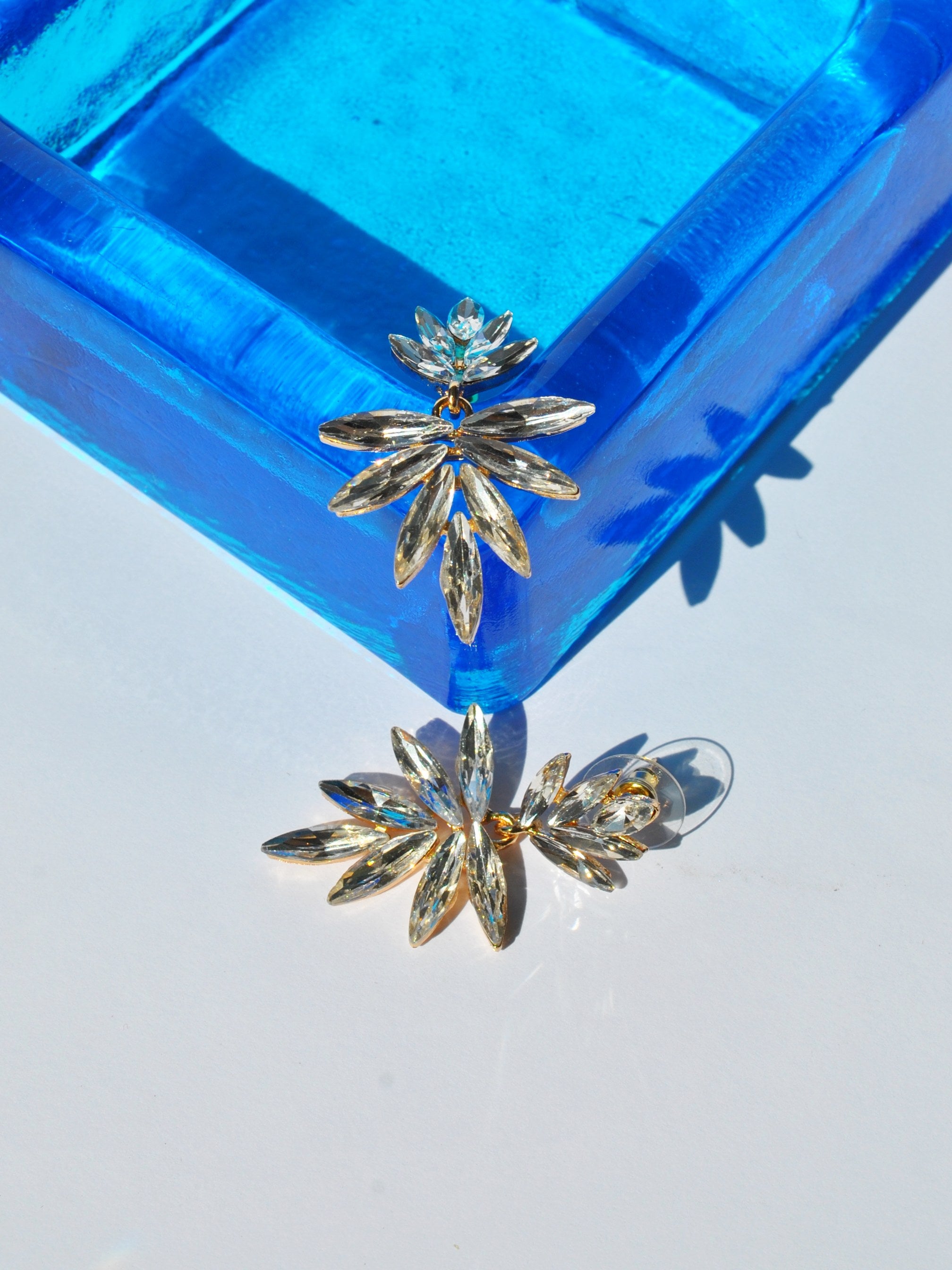 Glamorous crystal dangle earrings featuring modern botanical design and lightweight statement silhouette.