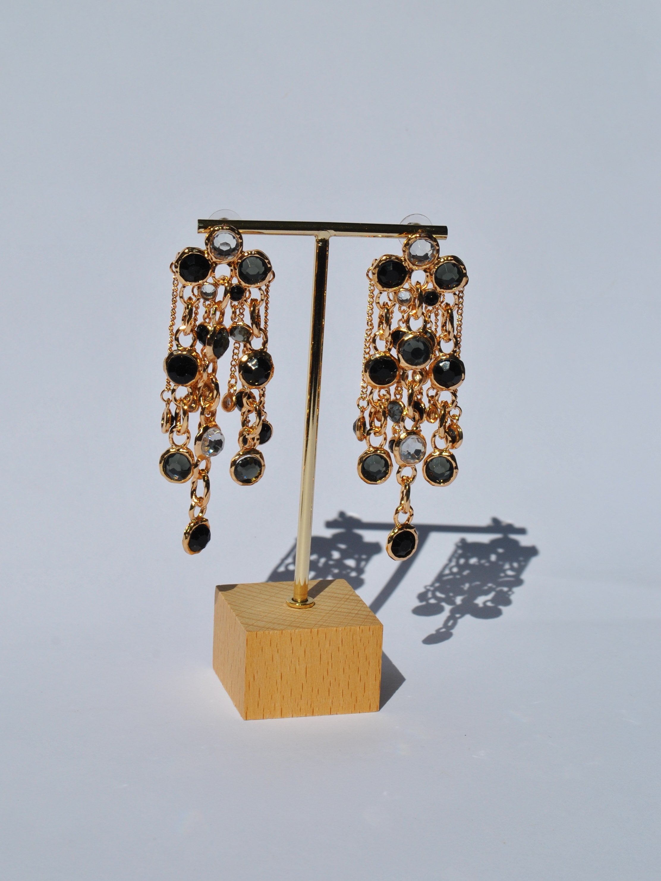 Trendy statement dangle earrings with black jewel detailing and glamorous gold finish for upscale party wear.