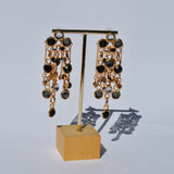 Trendy statement dangle earrings with black jewel detailing and glamorous gold finish for upscale party wear.