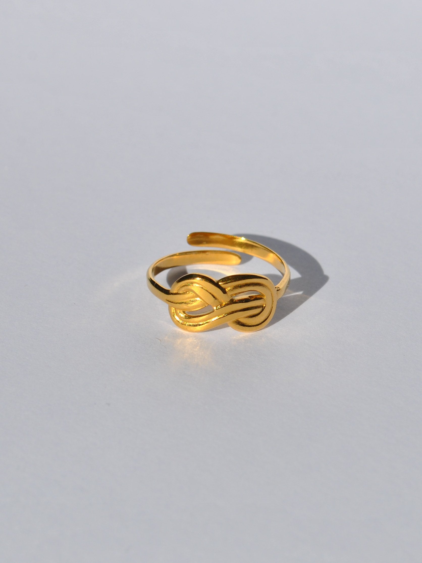 Chic gold open ring featuring a modern knot motif and polished metallic finish for trendy everyday jewelry looks.