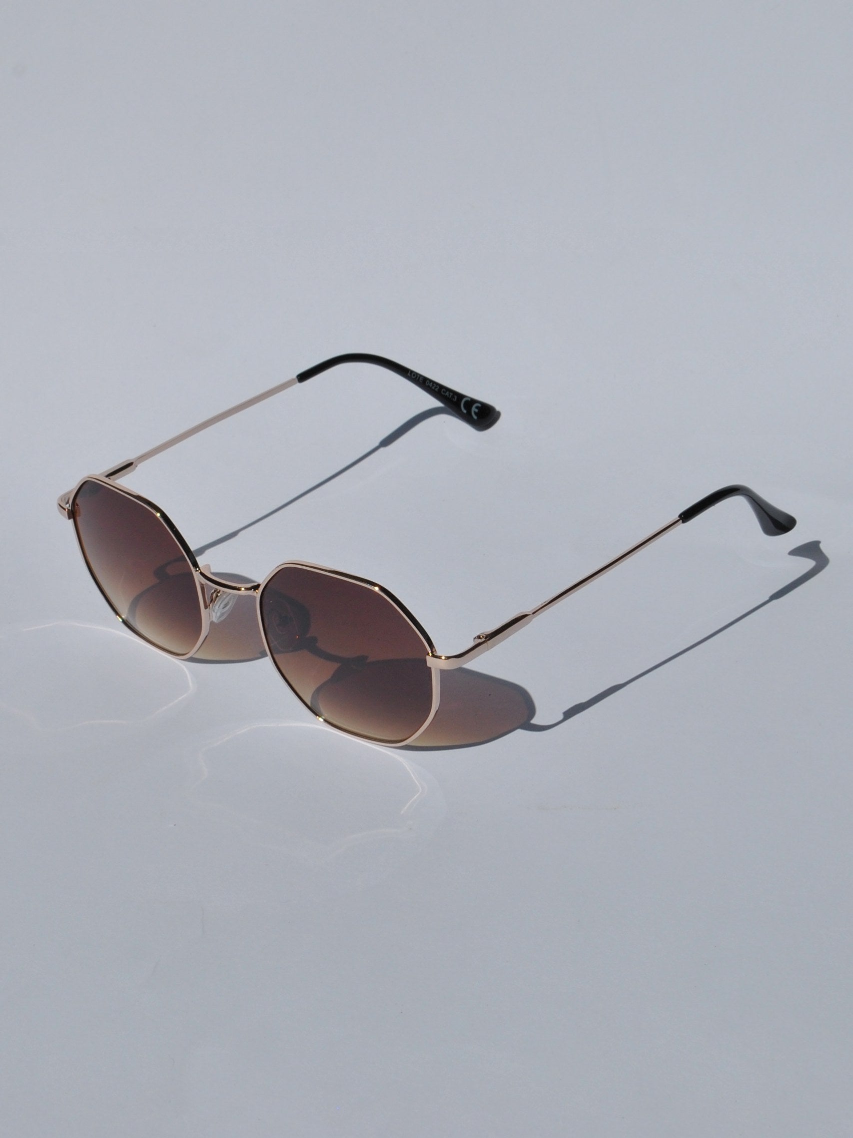Modern geometric sunglasses for women with slim gold metal frames and trendy oversized hexagon lens shape.