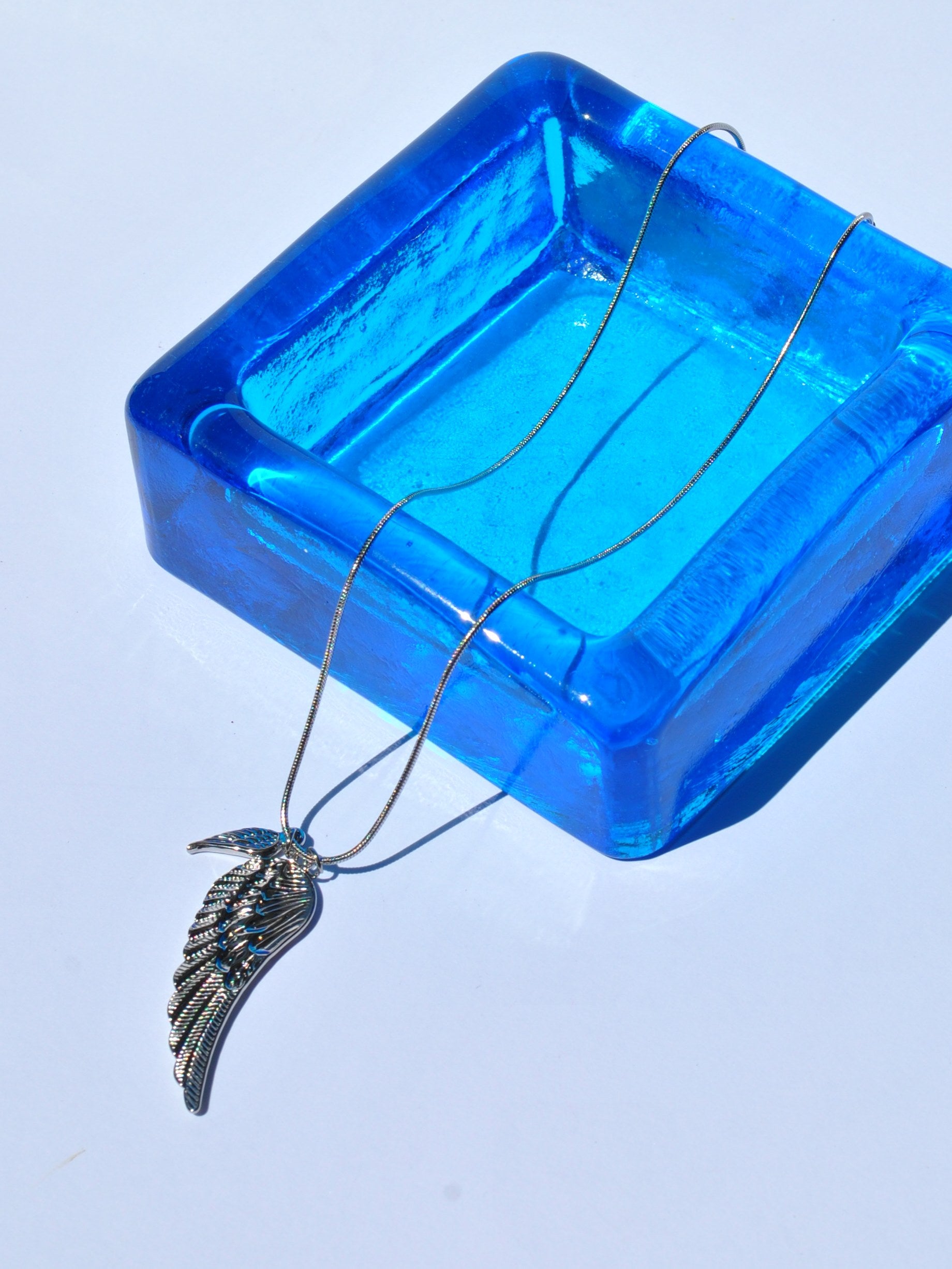 Gold wing statement necklace with feather-textured pendant and slim chain for trendy women’s fashion accessories.