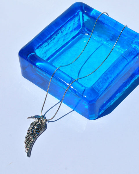 Gold wing statement necklace with feather-textured pendant and slim chain for trendy women’s fashion accessories.