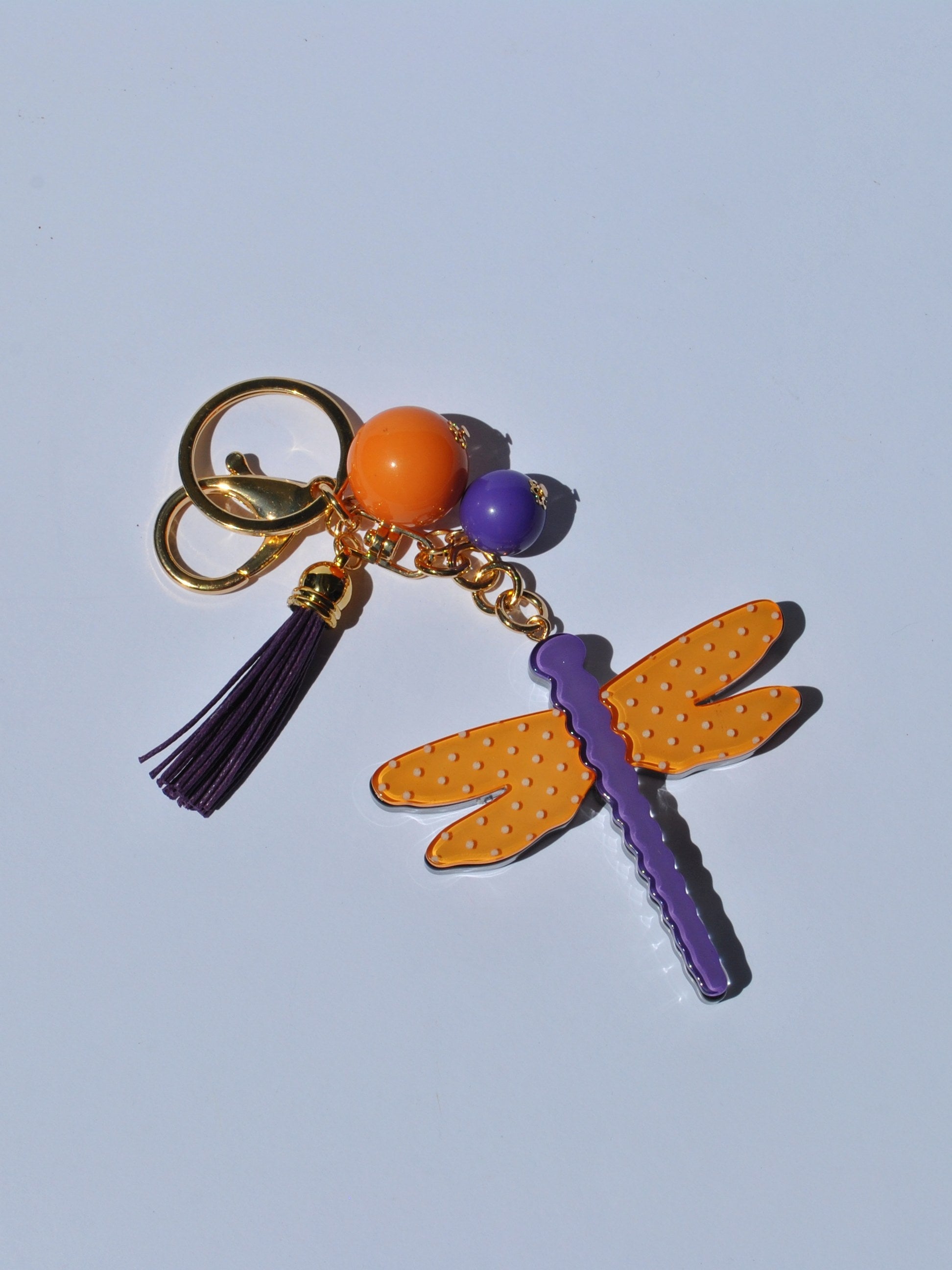 Fun fashion keychain with vibrant dragonfly pendant and decorative tassel for stylish backpack, tote, or handbag accessorizing.