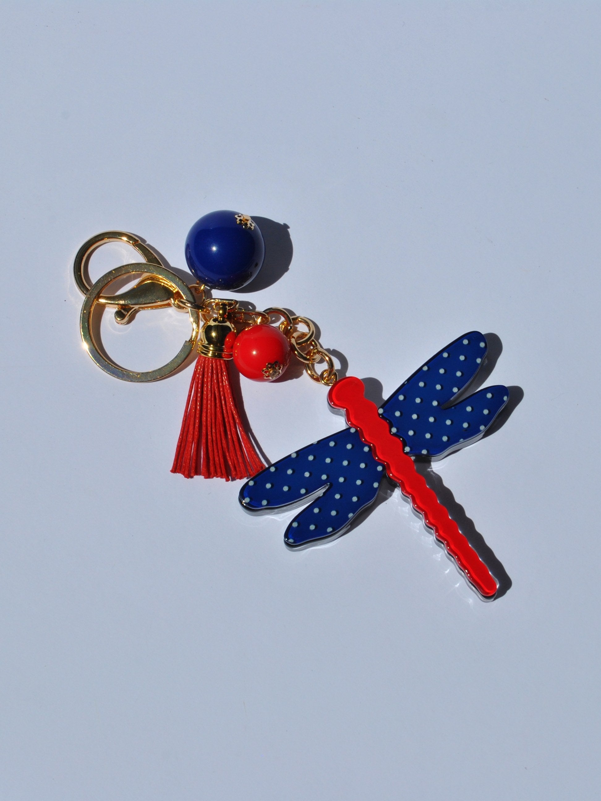 Playful women’s keychain accessory with navy spotted dragonfly charm and bright red details for modern boutique fashion.