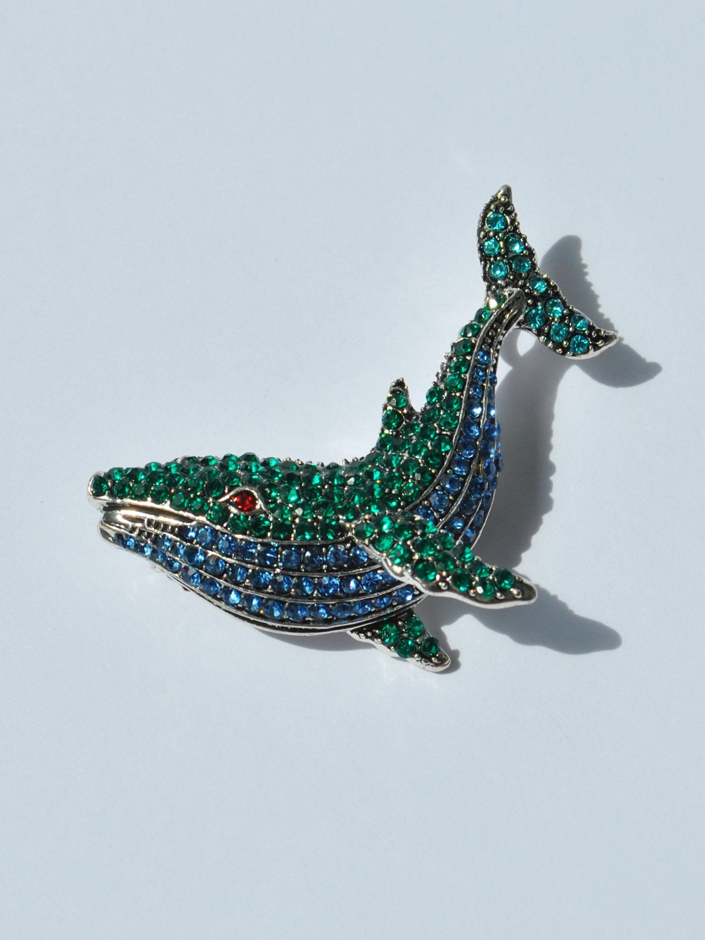 Elegant crystal whale brooch with green and blue rhinestones for nautical fashion.