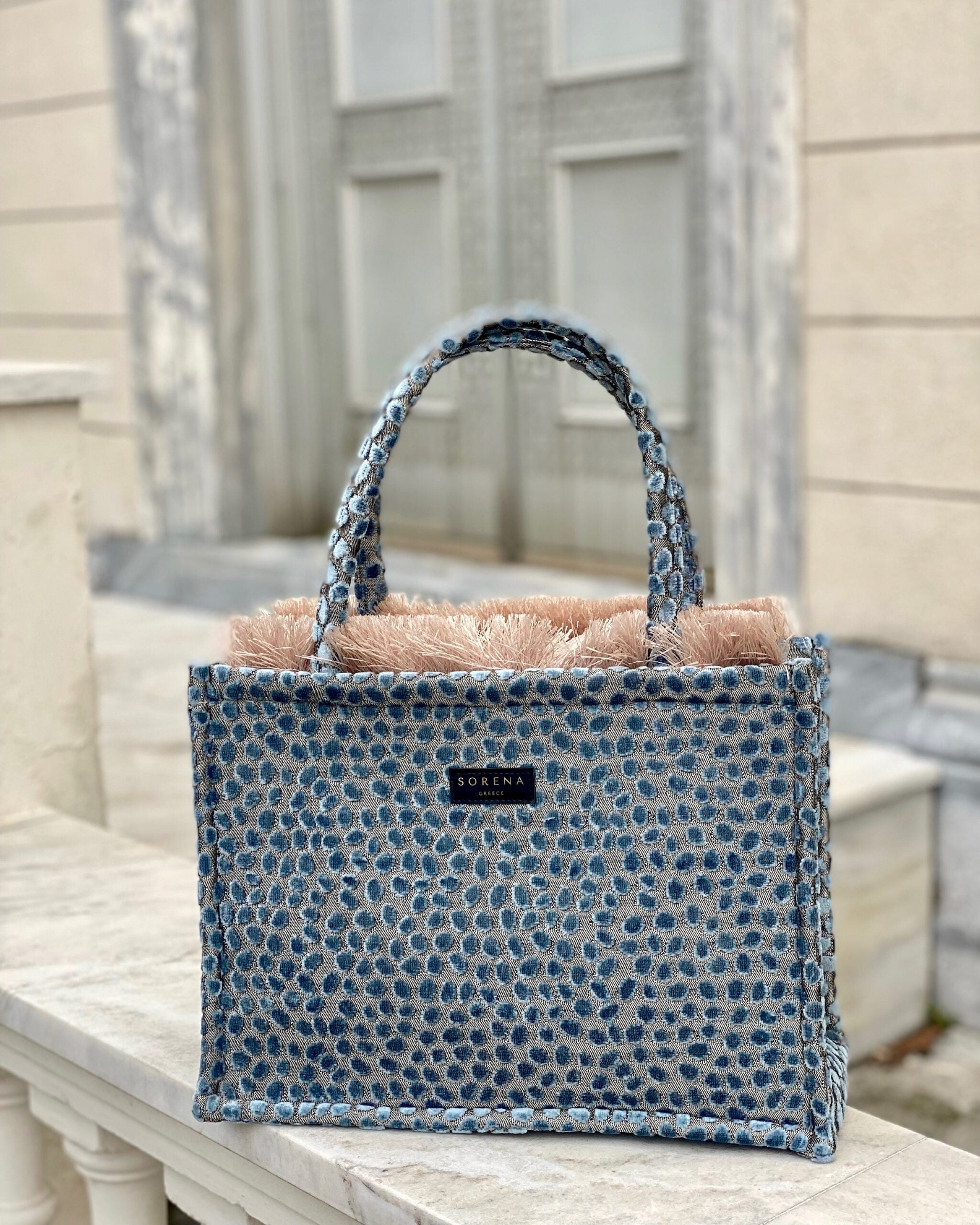 Elevated resort handbag with artisanal blue woven fabric and minimalist luxe aesthetic for vacation outfits.