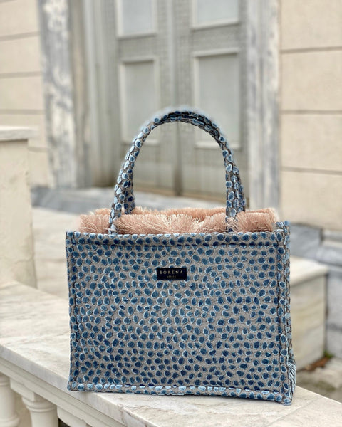 Elevated resort handbag with artisanal blue woven fabric and minimalist luxe aesthetic for vacation outfits.