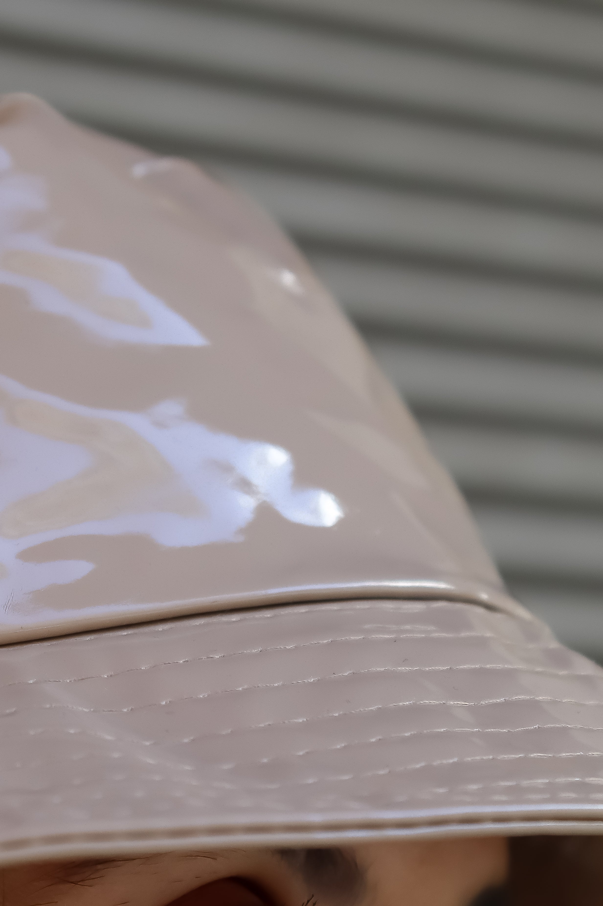 Stitching and detail of finish  of this women’s glossy beige bucket hat with modern minimalist styling and chic neutral-tone fashion aesthetic.