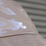 Stitching and detail of finish  of this women’s glossy beige bucket hat with modern minimalist styling and chic neutral-tone fashion aesthetic.