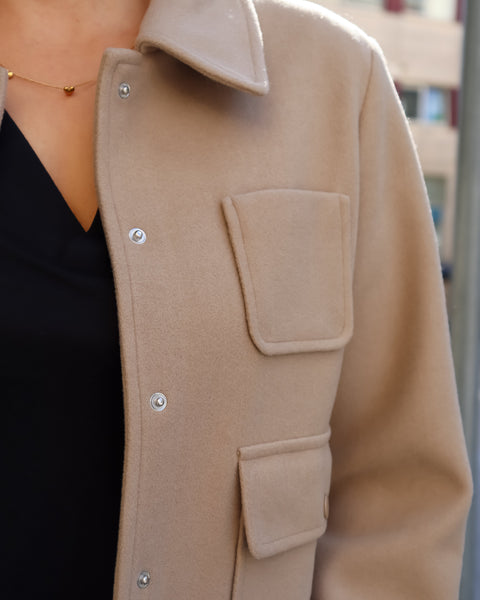 Detail of pockets and snaps of modern minimalist beige jacket with front pocket detailing and relaxed fit for effortless city-chic styling.