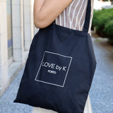 Large black shopper tote with contemporary logo Love By K design and functional minimalist fashion appeal.
