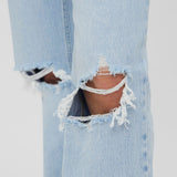 Casual light blue denim jeans featuring vintage-inspired fading and trendy knee distressing.