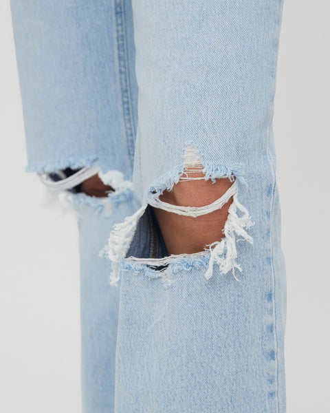 Casual light blue denim jeans featuring vintage-inspired fading and trendy knee distressing.